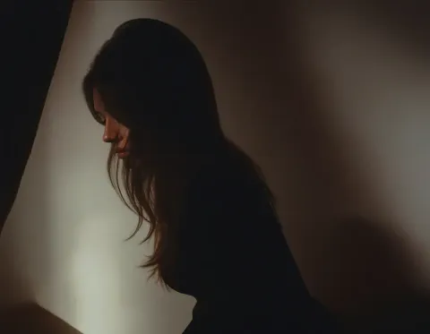 Window silhouette — A quiet side-profile silhouette near a softly lit window, warm brown tones and gentle film grain.