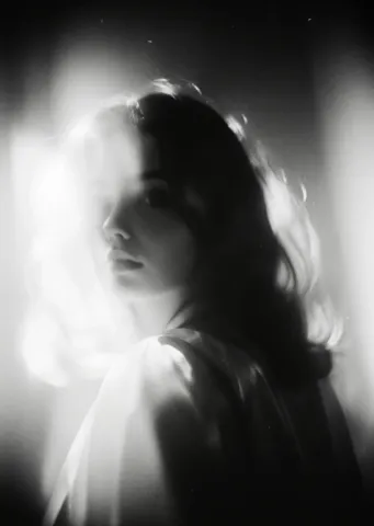 Soft monochrome light — A softly blurred monochrome portrait framed by bright window light, dreamy grain and luminous hair.