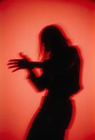 Red dance silhouette — A dancer silhouetted against a vivid red-orange background, blurred hands and flowing movement.