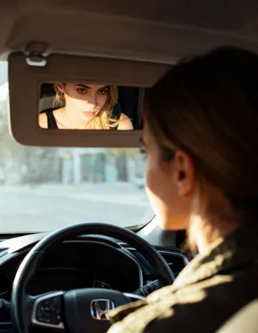 Rearview reflection — A cinematic rearview mirror reflection in a warm car interior, shallow depth of field and late-afternoon sunlight.