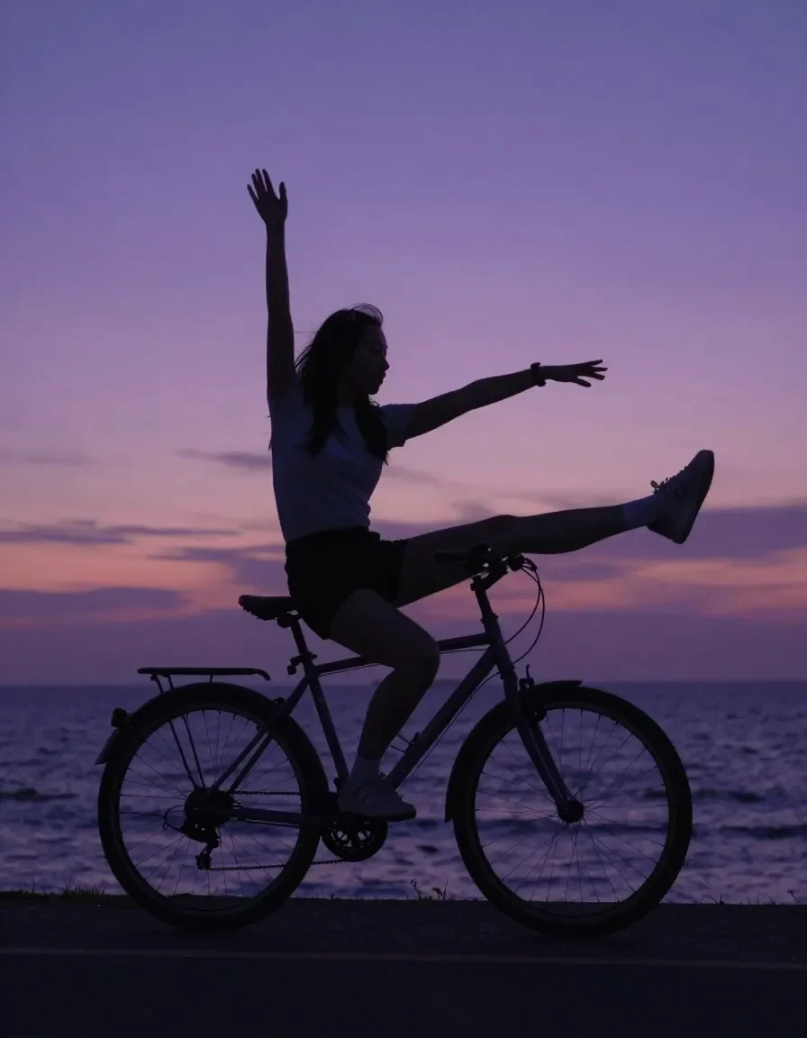 Bicycle sunset — A playful cyclist silhouette beside the sea at purple sunset, outstretched arms and a clean horizon.