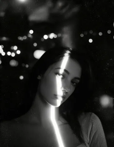 Night light portrait — A monochrome portrait with a narrow beam of light crossing the face, scattered city bokeh and deep shadows.